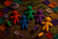 multicolored poppets surrounded by pieces of cloth, herbs, crystals, needle and thread. 